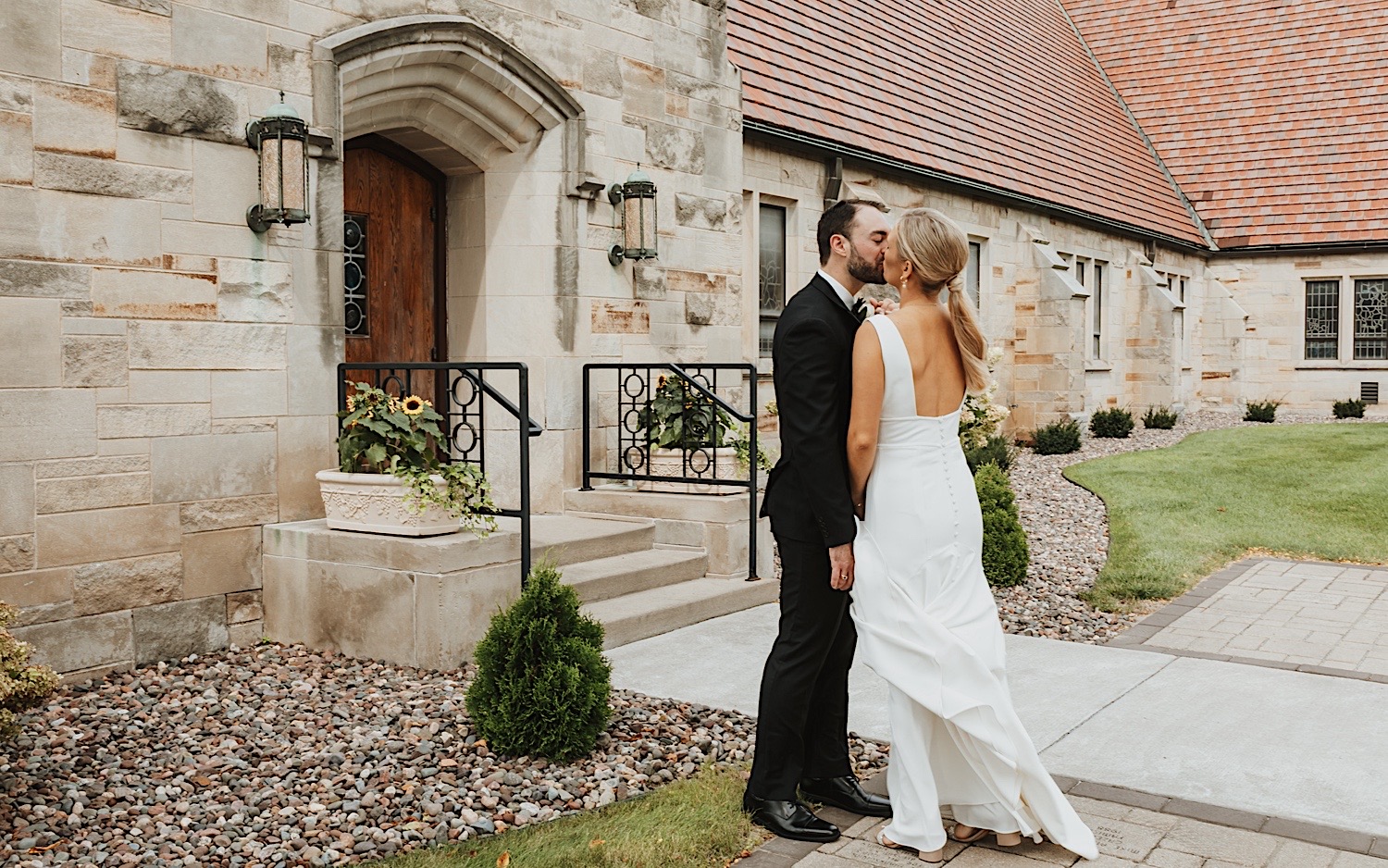 A bride and groom kiss outside of the church before their ceremony