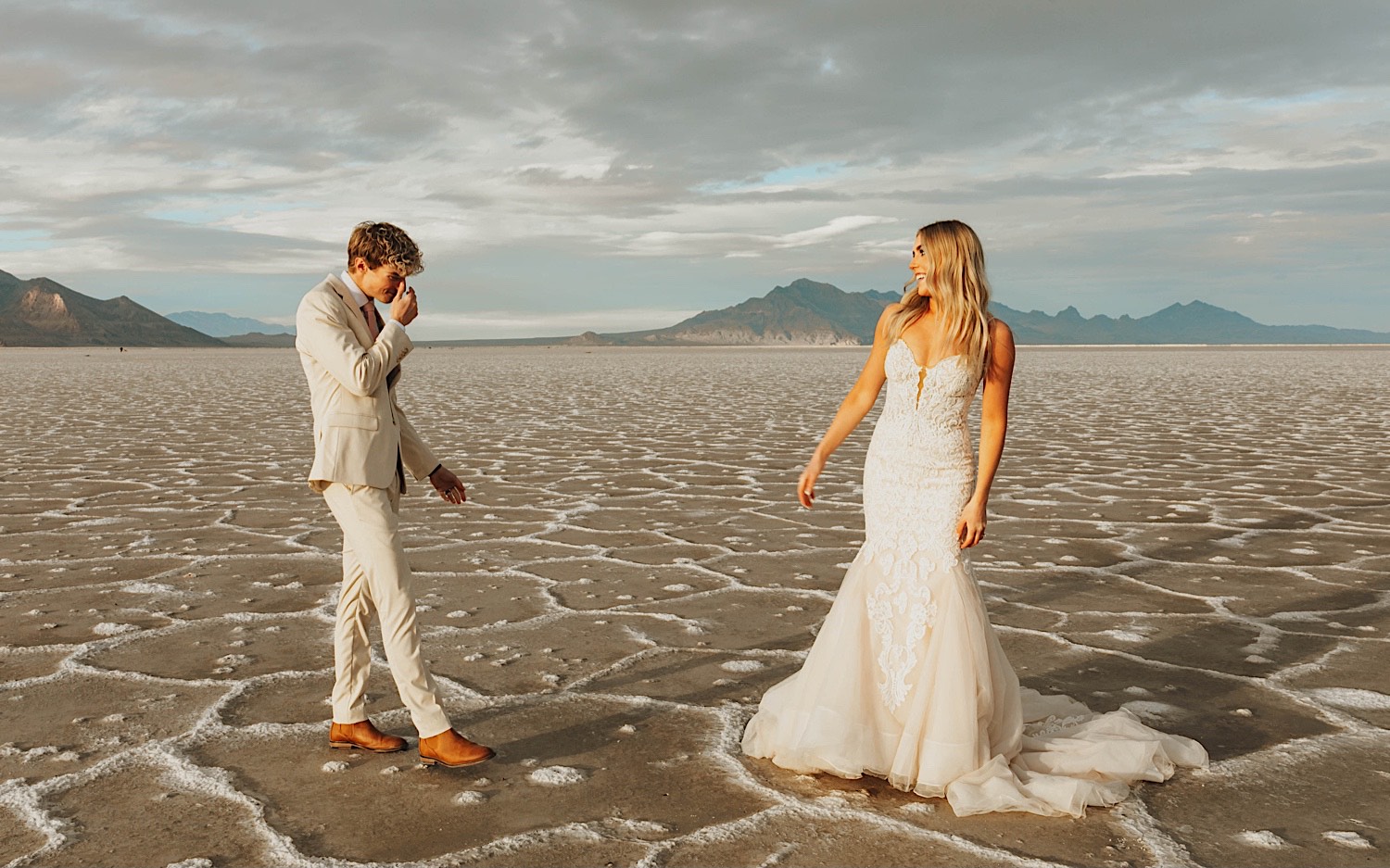 In the Utah Salt Flats, a groom gets emotional seeing the bride for the first time as she smiles at him before their elopement ceremony