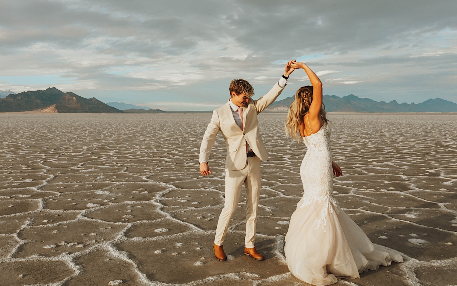 During their elopement in the Utah Salt Flats, a bride dances with the groom as he spins her around while holding her hand