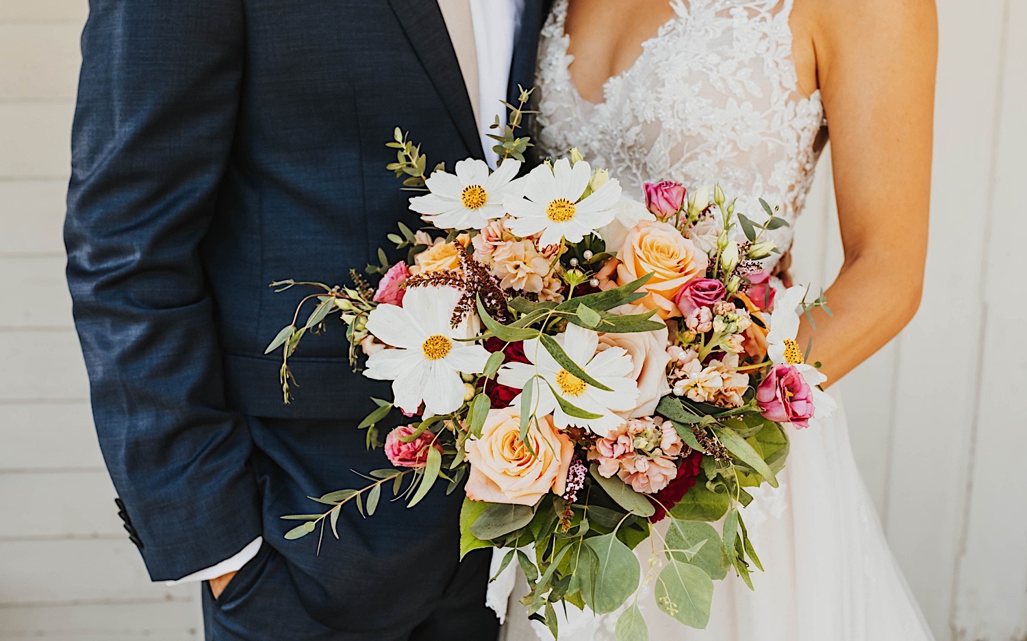 Close up photo of a flower bouquet being held by the bride while the groom stands at her side